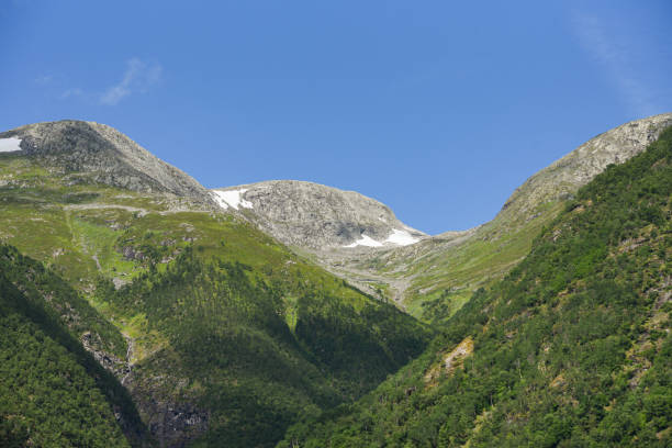 istock Norwegian mountain landscape where the mountain divides into several layers. Snow on the top of the fjord under a blue summer sky. 2191548319