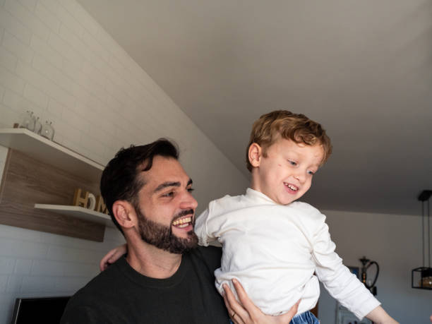istock Father joyfully holds son in cozy home during afternoon playtime 2191549895