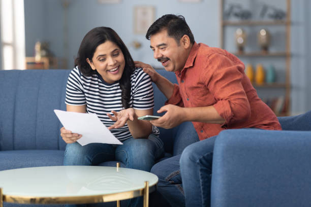 istock Happy couple reading document sitting on sofa at home stock photo 2191550024