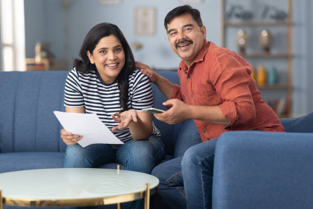 istock Happy couple reading document sitting on sofa at home stock photo 2191550065
