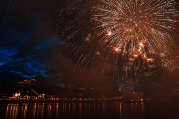 Fireworks burst brightly over the Danube River in Budapest, adding vibrancy to the night sky during national festivities on August 20th, enhancing the city\\'s beauty.