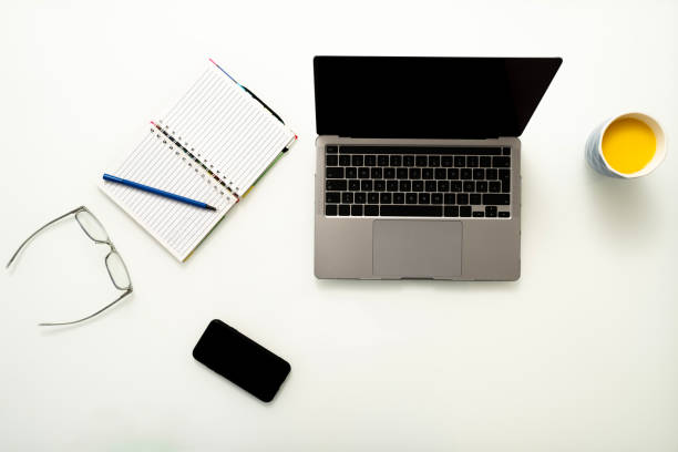 istock Modern white office desk table with laptop computer, phone, glasses, notebook and cup of juice top view with copy space, flat lay. 2191554051