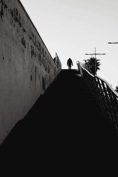 A person is climbing with great effort up the slope of a hill. Image that can be used as for labor, psychological, financial, ... Copy space