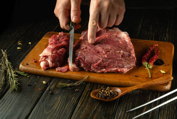 istock Skillful hands expertly slice fresh meat on a wooden cutting board in a rustic kitchen 2191563529