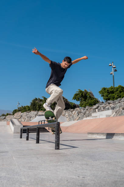 istock young skater wearing black tshirt does a trick in a skate park rail. 2191571620