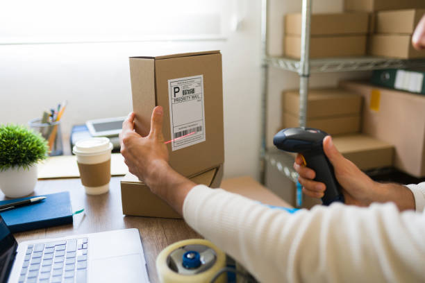 istock Closeup of a man preparing a shipment and scanning a barcode on a cardboard box in a warehouse using a barcode scanner 2191573458
