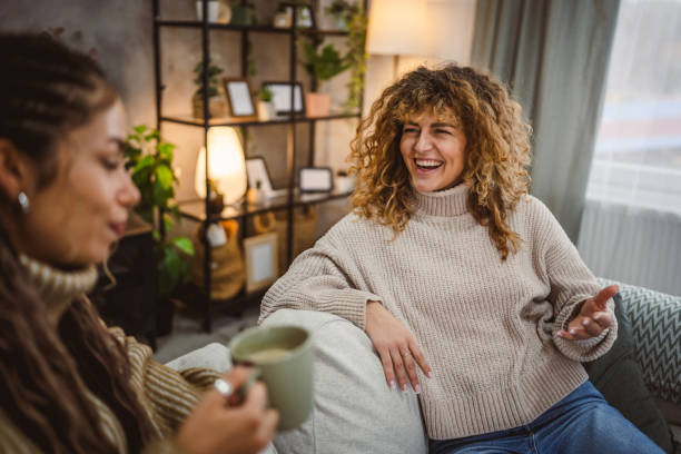 istock two young adult female friends sit on sofa and enjoy while chatting 2191574681