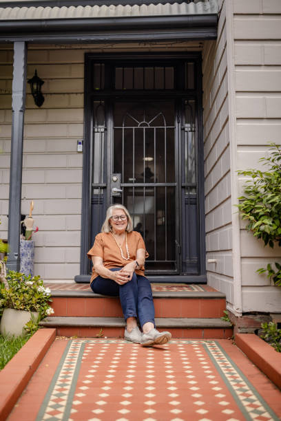 istock Senior woman sitting alone on porch step, smiling. 2191575745