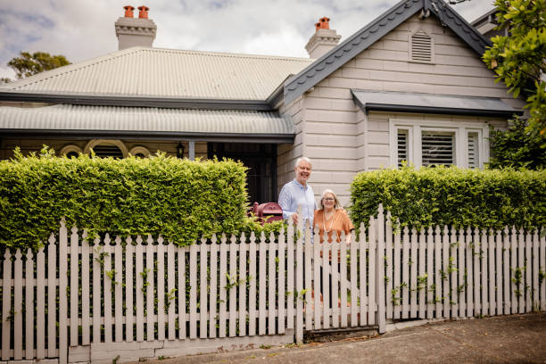 istock Smiling elderly couple at a white picket fence entry. 2191575854