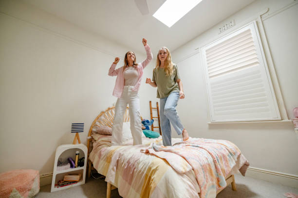 istock Women dancing energetically on bed, sunlight fills room 2191577110