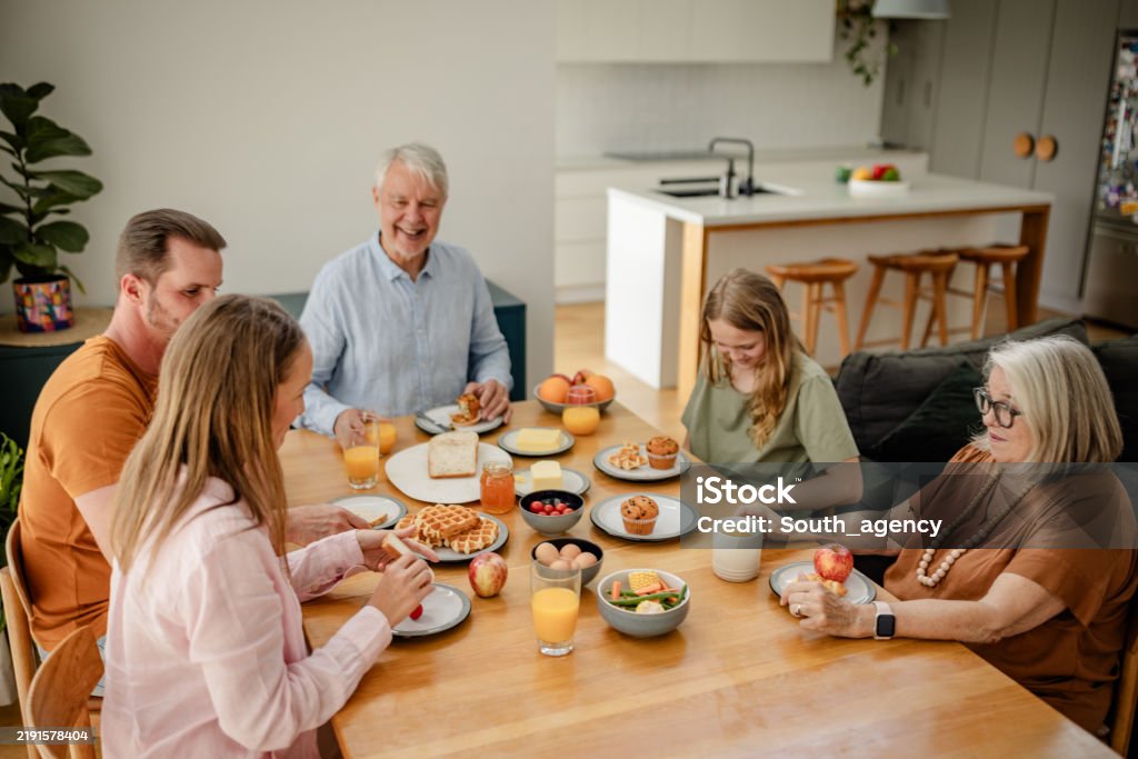 Joyful family breakfast in a modern kitchen setting - Royaltyfri Australiensisk kultur Bildbanksbilder Joyful family breakfast in a modern kitchen setting - Royaltyfri Australiensisk kultur Bildbanksbilder