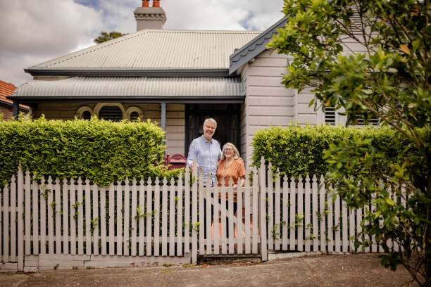istock Elderly couple posing happily by white picket fence. 2191586181