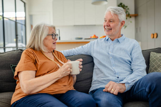 istock Elderly couple talks and smiles while sitting on sofa. 2191586242