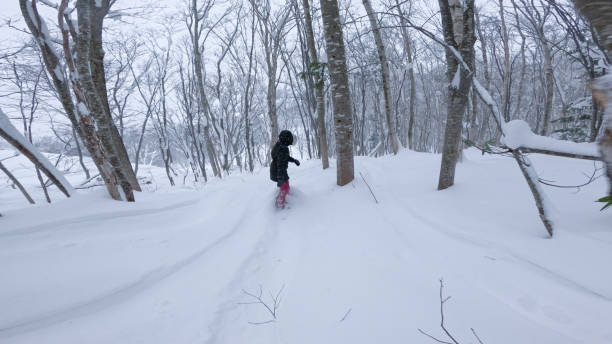 istock Female snowboarder manoeuvres through snowy forest while riding fresh powder 2191587296