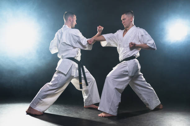 istock Martial arts masters on dark background. Strong man fighters in white kimono for karate martial arts fighting training in black gym, Karate fighters training punches kicks practicing fight sparring 2191592865
