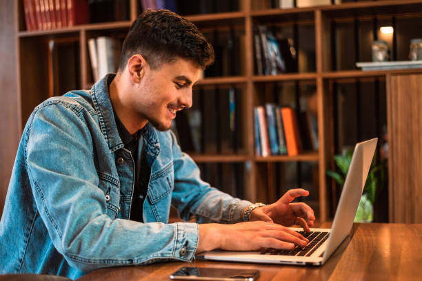 istock A happy male college student using a laptop in a university library. 2191593377