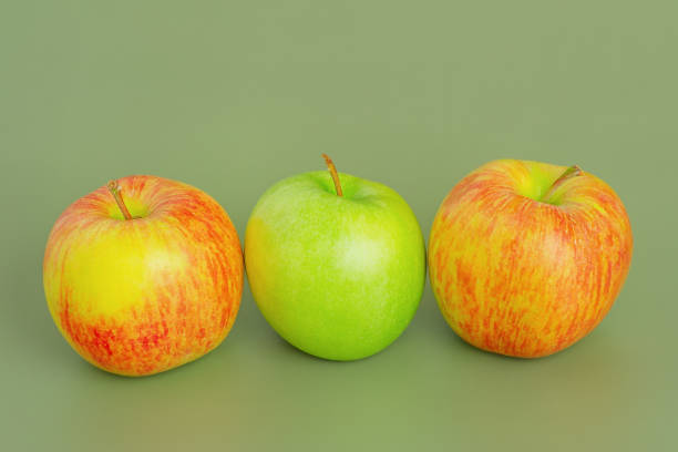 istock Two red and yellow apples and one green apple. Fruit, apples on a green background. 2191595407