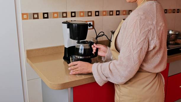 istock Woman preparing a coffee at a kitchen counter wearing a beige apron 2191601878