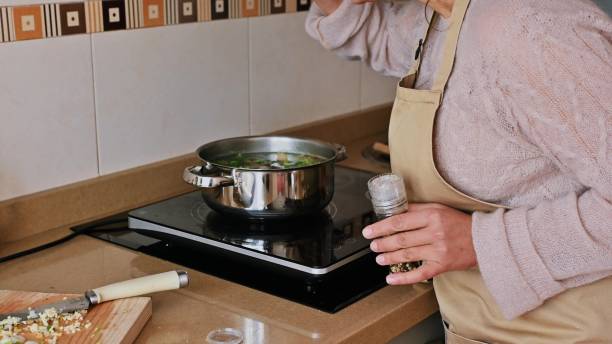 istock Woman seasoning soup while cooking at home in a modern kitchen 2191601883