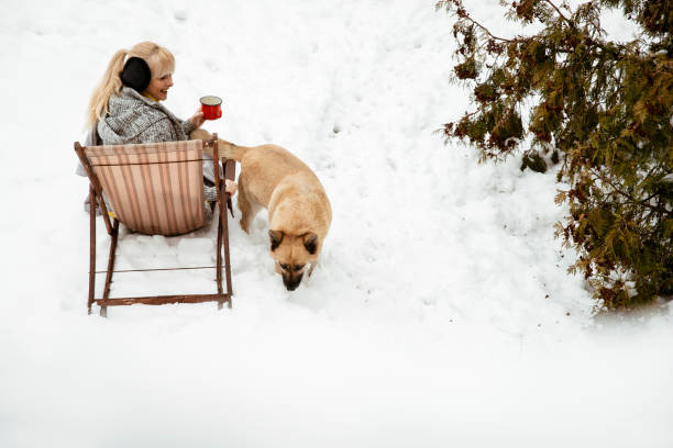 Woman and dog in Winter landscape in garden covered with snow. Wonderful relaxation with pets