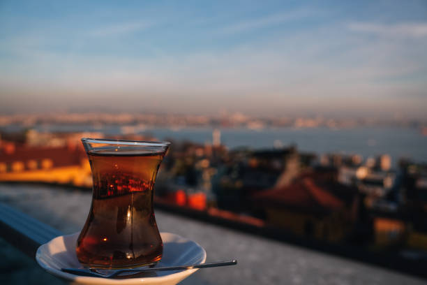 Turkish tea served in a tulip-shaped glass on a rooftop terrace with a view of the Istanbul cityscape