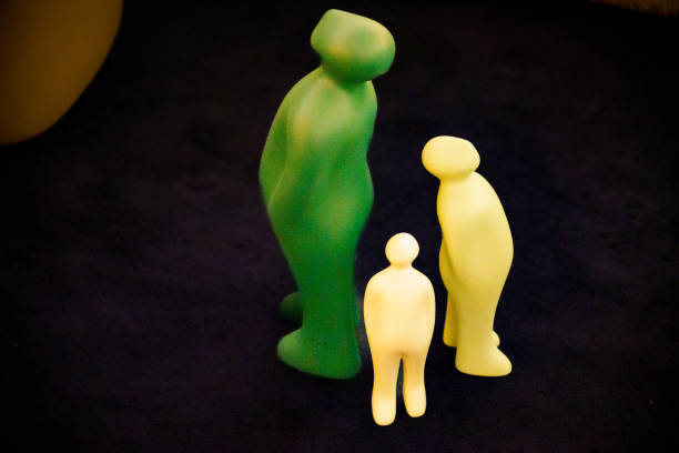 Three ceramic figures depicting a human in green tones, standing with their backs to each other