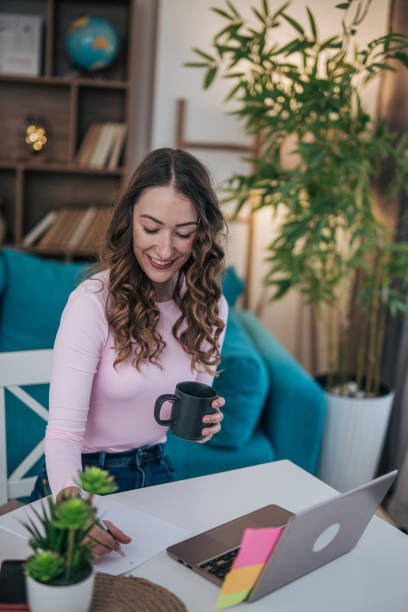 istock Young woman writing notes on a piece of paper while working at her desk 2191607887