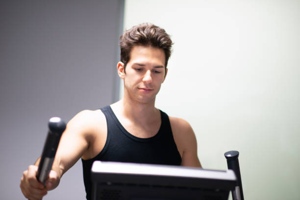 istock Young Man Working Out on Elliptical Trainer in Gym 2191608711