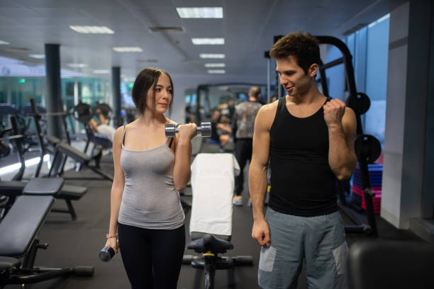 istock Young Couple Lifting Weights and Exercising Together in Gym 2191609261