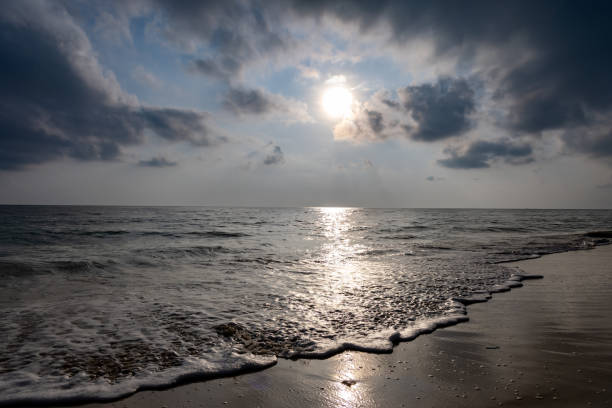 sea horizon with bright sunrise blue sky from sandy beach and rolling waves at morning