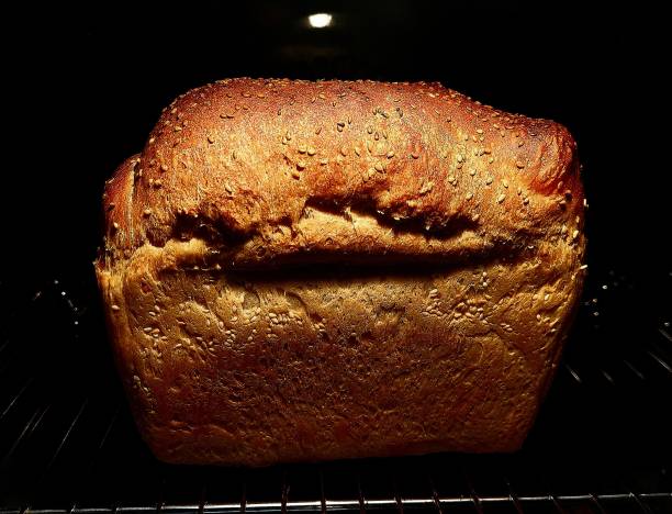 Fresh loaf of bread on black background, impressive texture.