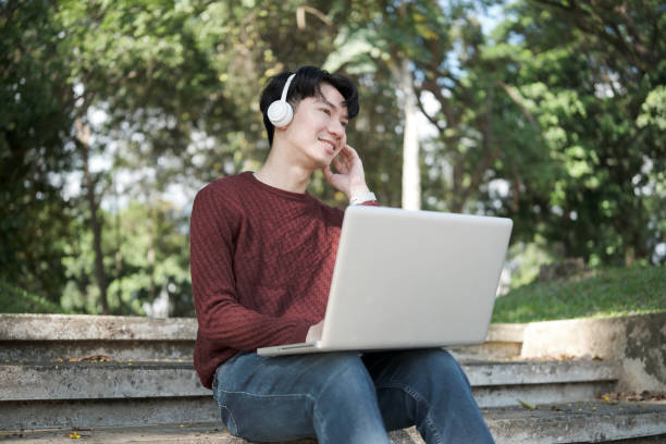 istock Young college student working on his laptop, studying outdoors while sitting on the steps in a campus park on a sunny day 2191620490