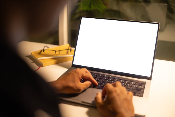 istock Close up of hands typing on a laptop with a blank white screen at ight. 2191620647