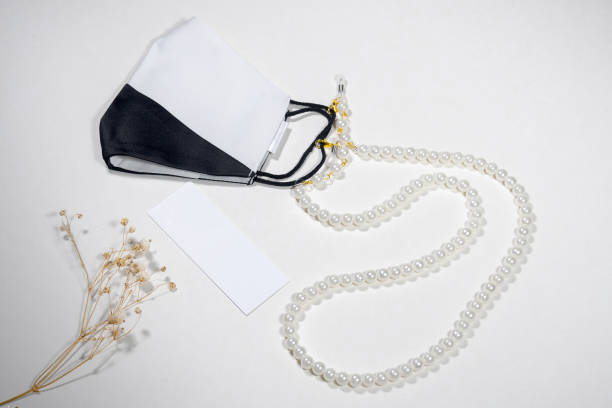 istock A face mask that is half black and half white, attached to a chain made of clear beads. 2191627364