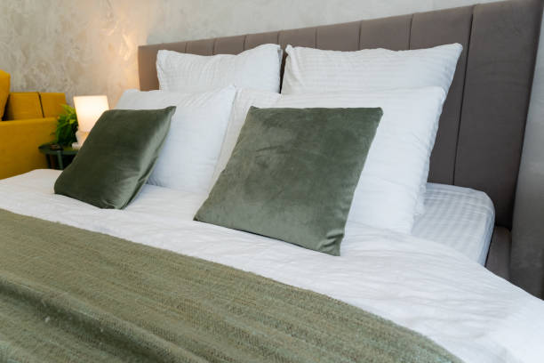 istock A cozy hotel room features a bed with white sheets and green pillows 2191628898