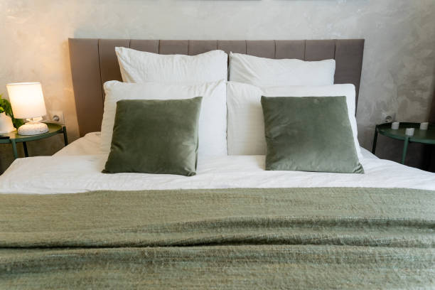 istock A cozy bed with white sheets and green pillows occupies a warm bedroom 2191628912