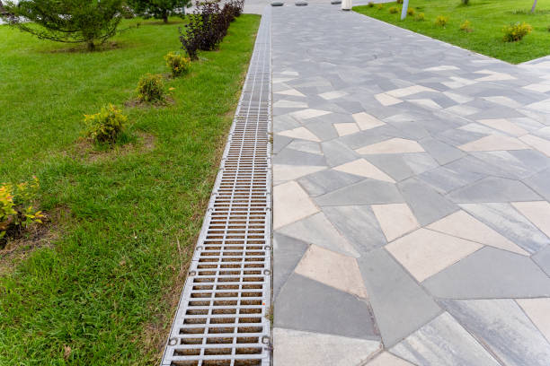 A metal drain is by a brick walkway in a park area