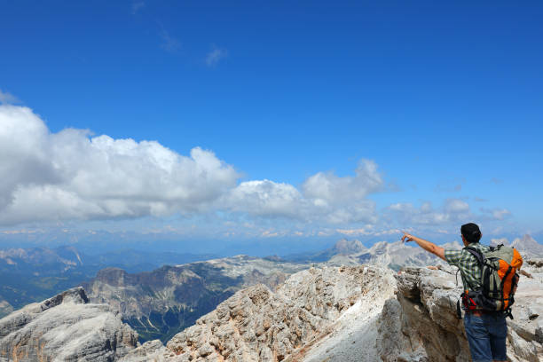 istock male hiker with a backpack and cap pointing with his finger at the mountain summit he plans to reach 2191634217