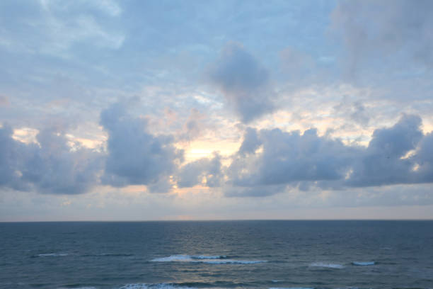 Sunlight filtering through low clouds at sunset and the sea below with some waves, ideal as a religious concept of God or a natural background