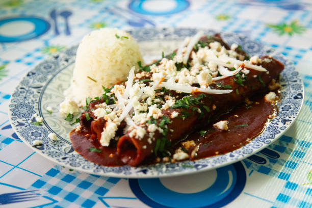 istock Traditional enchiladas with Oaxaca cheese, red mole and rice. Enchiladas are a dish from Mexican cuisine made with rolled or folded corn tortillas. 2191641089