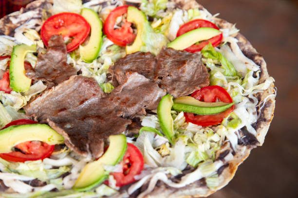 Tlayuda is a thin, crispy tortilla topped with black beans, beef jerky, tomato and avocado. Is a traditional Mexican food from Oaxaca..