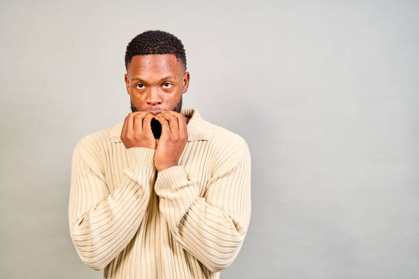 istock Worried young man biting his nails on a grey background 2191659524