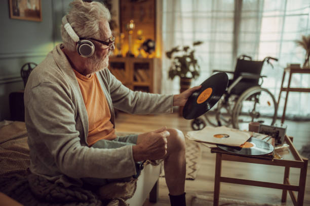 istock senior man with a disability listening to music while holding gramophone records 2191660149