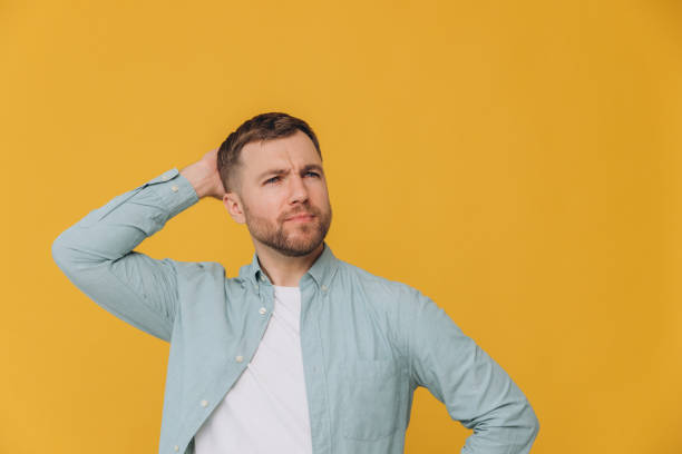 istock Bearded man wearing casual clothes thinking concentrated about doubt with hand on head and looking up wondering on yellow background with copy space 2191660159