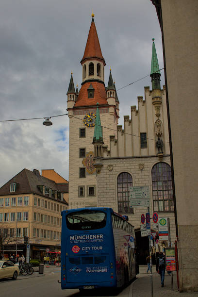 Munich, Germany - October 22, 2024: The historic Old Town Hall with its distinctive architecture and clock tower stands majestically in Munich. A blue tour bus drives past the iconic building.