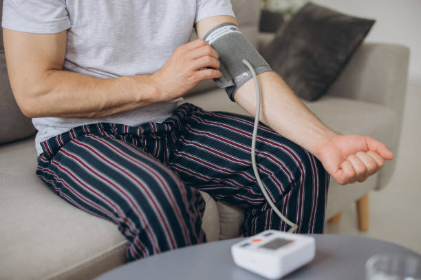 istock Close-up male sitting on couch at home, checking blood pressure. Man using modern tonometer, experiencing hypertension caused by stress, copy space 2191663108