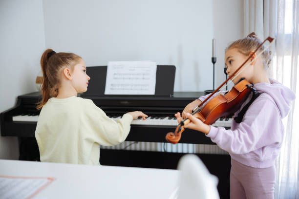 istock Two sisters having fun practicing piano and violin together 2191663460