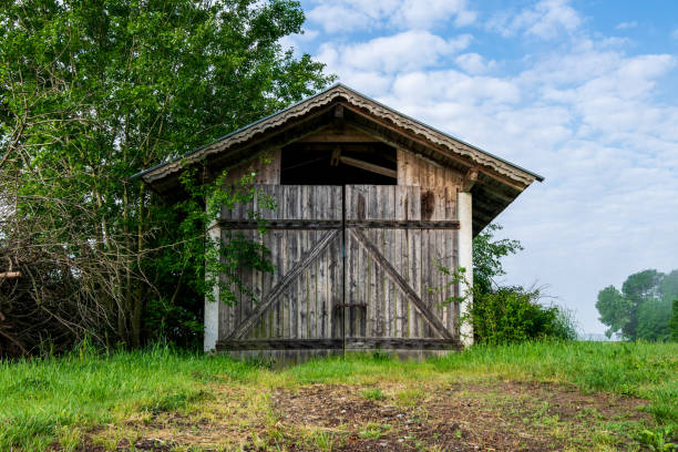 istock Old Barn with clouds and grass in the bavarian forest and a field in front of 2191663872