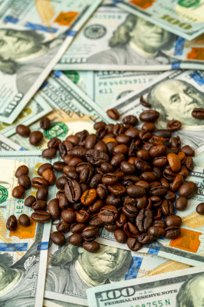 istock Coffee beans scattered on a pile of hundred dollar bills 2191666160