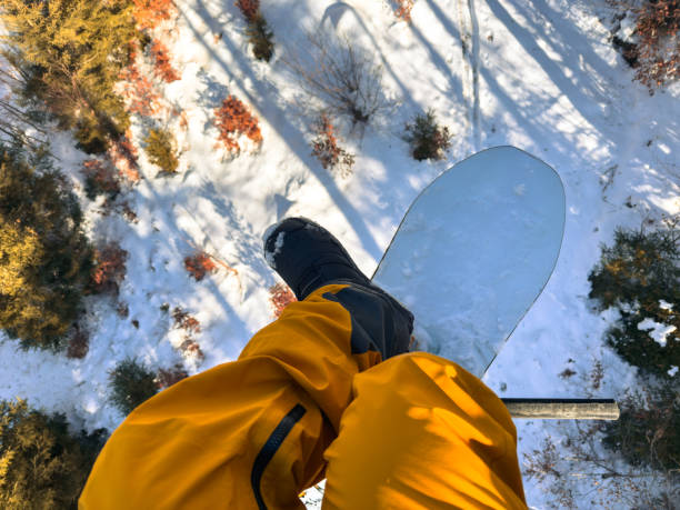 Snowboarder on a Ski Lift Above Snowy Terrain